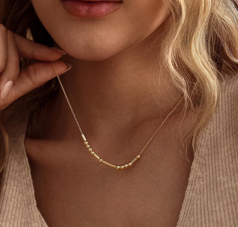 Gold Morse code necklace worn at the collarbone