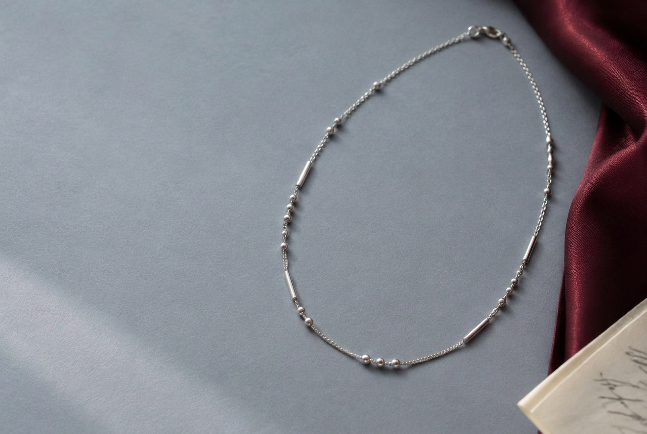 Silver Morse code necklace in an editorial still life
